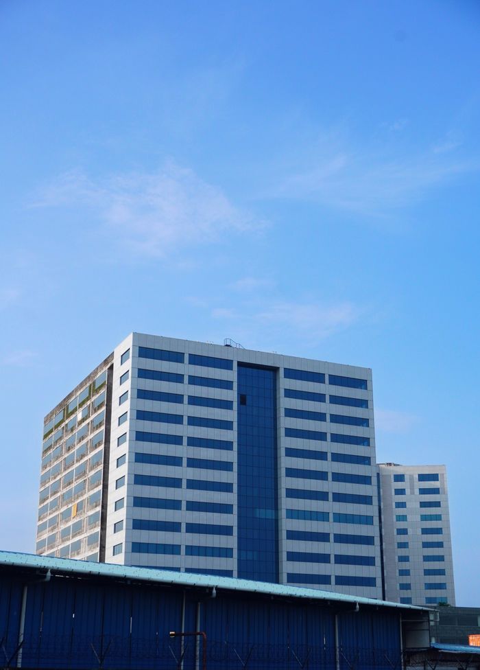 A tall office building in Kochi, India with a bright blue sky background.